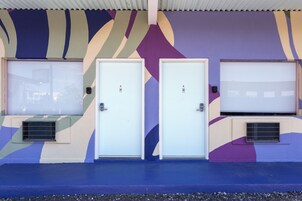 Two white doors with air conditioning vents, set against a wall with a geometric pattern.