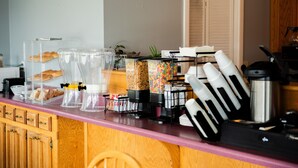 A kitchen counter with various appliances and containers, including a coffee maker, a blender, and containers with food items. - Cottonwood Inn (Salem)