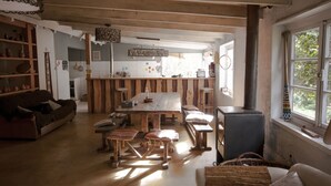 Um interior rústico com uma mesa de jantar de madeira, bancos, um sofá e uma lareira.