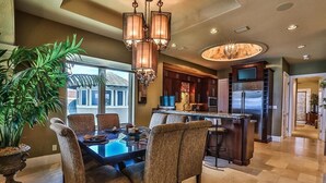A spacious dining area with a large table and chairs, a chandelier, and a view of the outside.