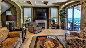 A spacious living room with a fireplace, comfortable seating, and a large TV.