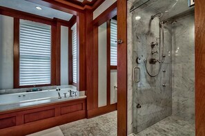 A bathroom with a large bathtub, a shower, and wooden paneling. - OLYMPIA CORAL SUITE 3 Bedroom Holiday Home by Five Star Properties (Destin)