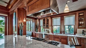 A spacious kitchen with a central island, wooden cabinetry, and large windows. - OLYMPIA CORAL SUITE 3 Bedroom Holiday Home by Five Star Properties (Destin)