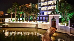 A multi-story hotel with a pool area, palm trees, and a wooden deck. - OLYMPIA CORAL SUITE 3 Bedroom Holiday Home by Five Star Properties (Destin)