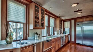 A modern kitchen with wooden cabinets, stainless steel appliances, and a large island with a sink.