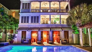 A two-story hotel with a swimming pool, outdoor seating, and a covered patio area.