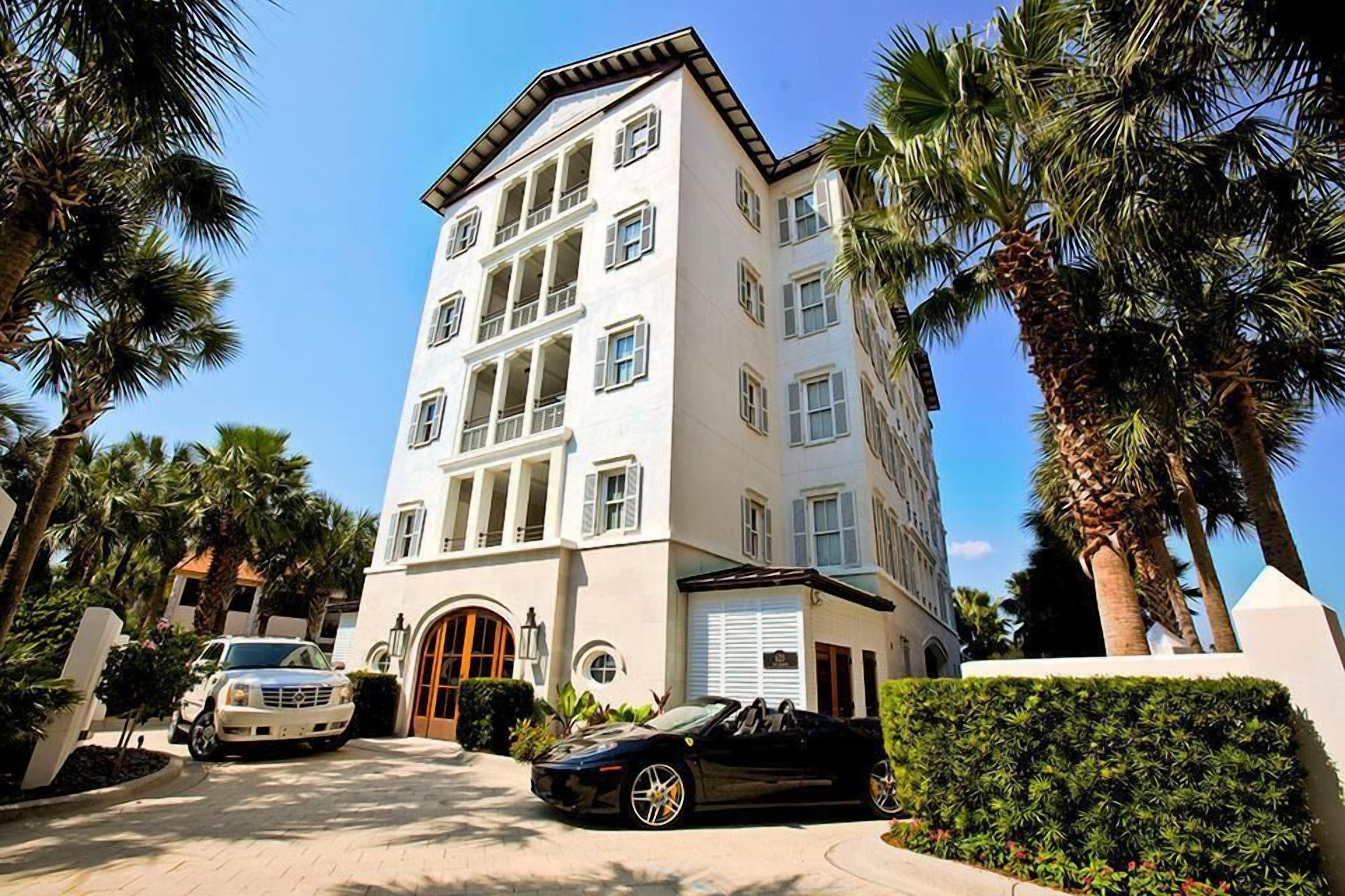 A multi-story hotel with a white facade, large windows, and a central entrance.