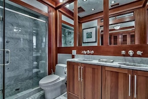 Un baño moderno con cabina de ducha de vidrio, inodoro y armarios de madera.