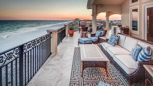 A balcony with a view of the ocean at sunset, furnished with a sofa, chairs, and a table. - Palazzo del Mar 11 Bedroom Holiday Home by Five Star Properties (Destin)