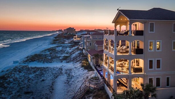 A beachfront property with a multi-story building, balconies, and a view of the ocean at sunset. - Palazzo del Mar 11 Bedroom Holiday Home by Five Star Properties (Destin)