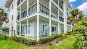 Un hôtel à plusieurs étages doté de balcons, d’un espace extérieur couvert aménagé en coin salon et d’un jardin bien entretenu.
