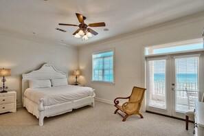 A bedroom with a bed, nightstands, a chair, a ceiling fan, and a view through the window.