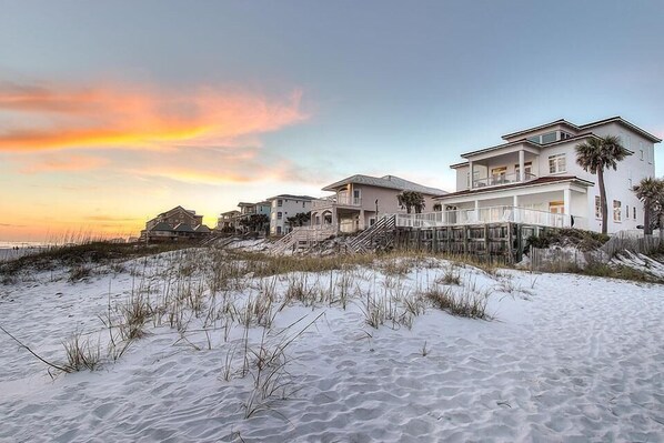 A beachfront property with multiple houses, a wooden walkway, and a sandy beach.