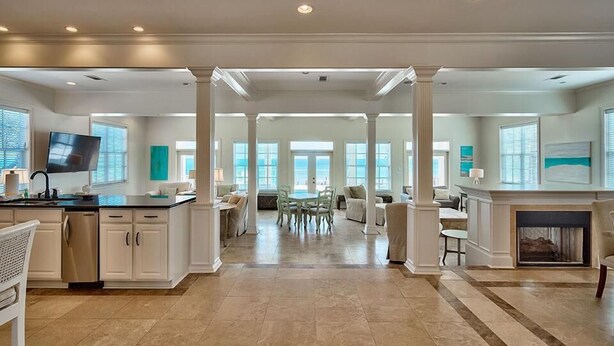 A spacious kitchen with a dining area, large windows, and a fireplace. - Redefining Beach Time 7 Bedroom Holiday Home by Five Star Properties (Destin)