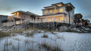 A beachfront property with a large house, a covered deck, and a sandy beach. - Redefining Beach Time 7 Bedroom Holiday Home by Five Star Properties (Destin)
