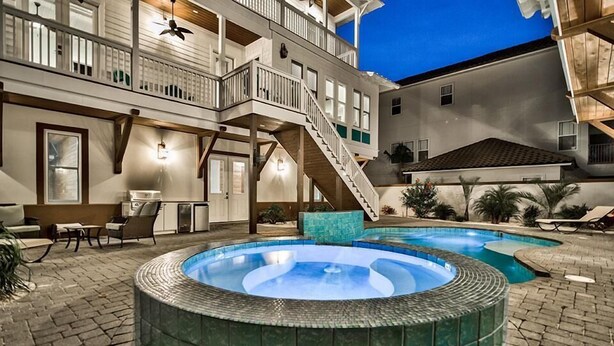A two-story building with a hot tub in the backyard, outdoor seating, and a staircase leading to the upper level.