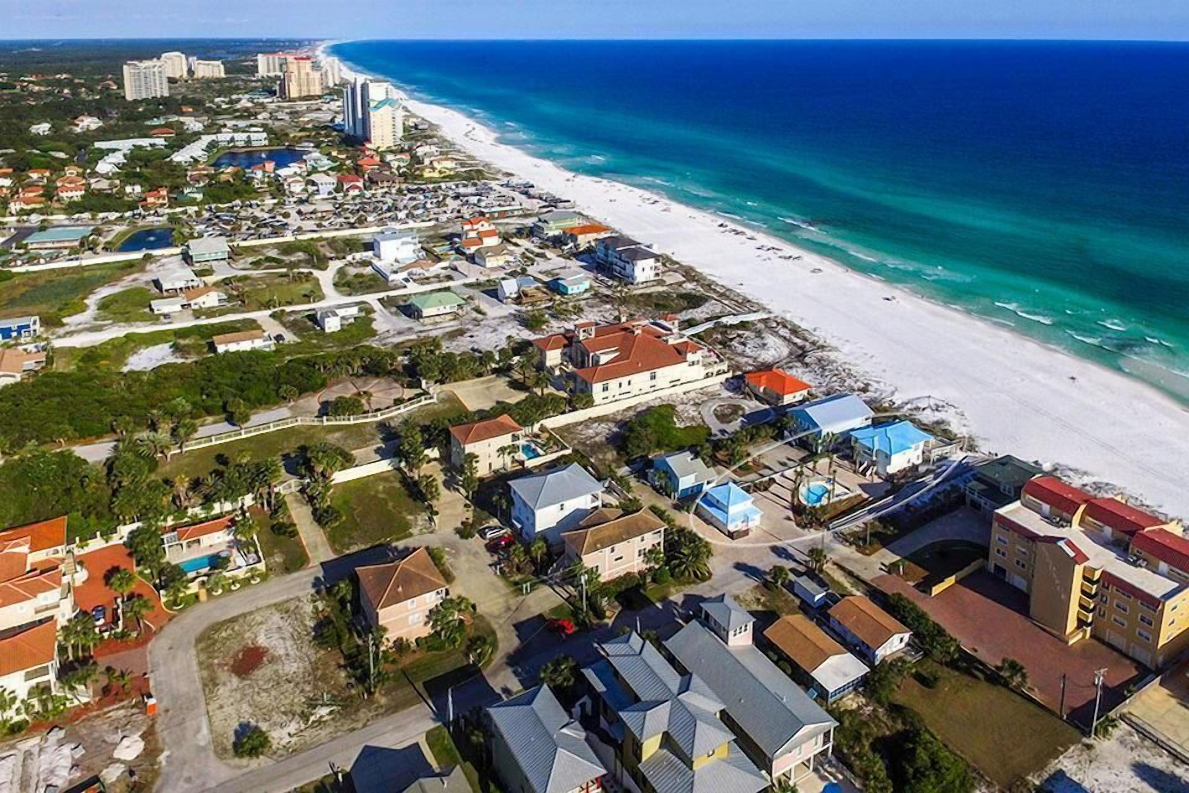 An aerial view of a coastal town with beachfront properties, roads, and buildings.