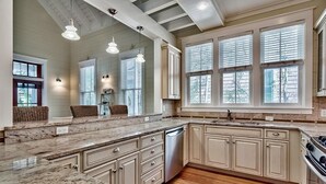 Una cucina con un piano di lavoro in granito, mobili in legno, lavastoviglie in acciaio inossidabile e forno integrato.
