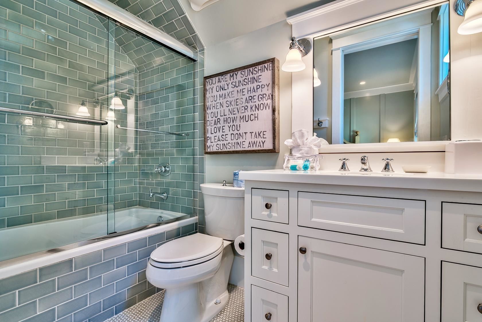 Une salle de bain avec une douche à parois de verre, des toilettes blanches et un meuble-lavabo doté de tiroirs et d’un miroir.