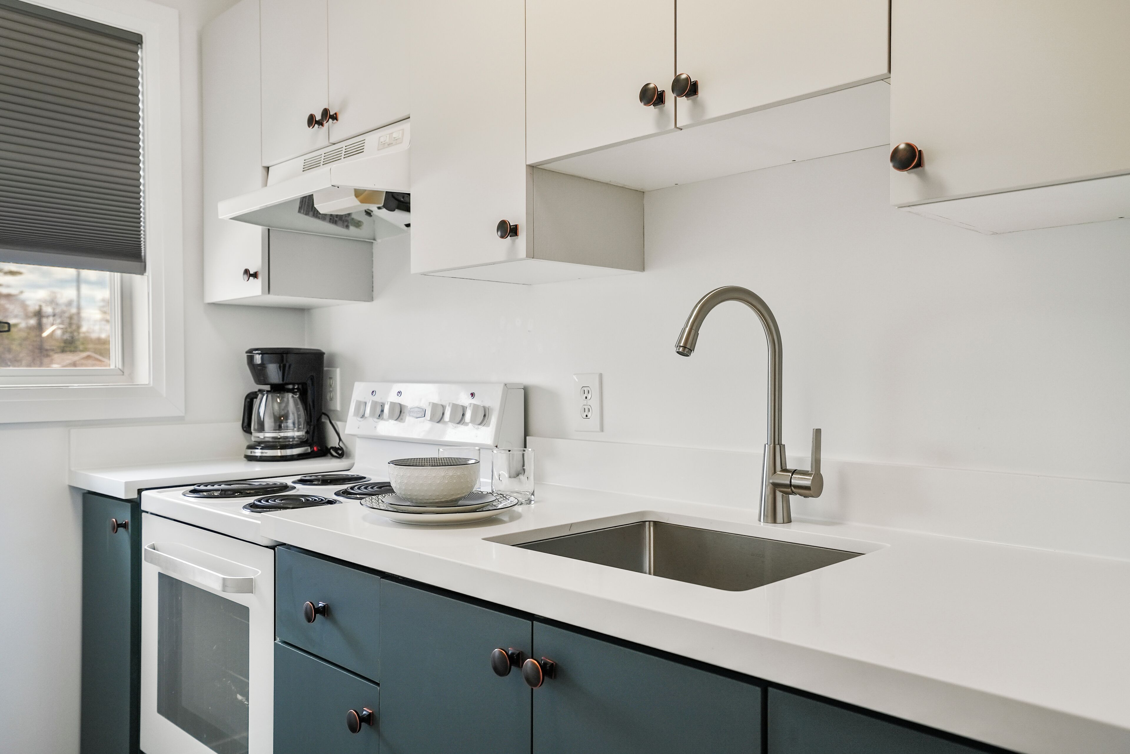 A modern kitchen with white cabinets, a stainless steel sink, and a built-in oven.