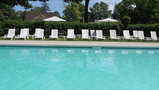 A swimming pool with white lounge chairs and umbrellas. - Saga Resort (Wasaga Beach)
