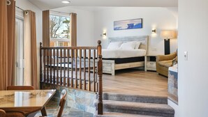 A hotel room with a bed, a desk, a chair, a staircase, and a view of the outdoors. - Saga Resort (Wasaga Beach)