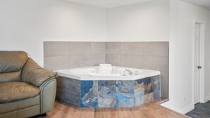 A modern bathroom with a freestanding bathtub, a leather chair, and a door. - Saga Resort (Wasaga Beach)
