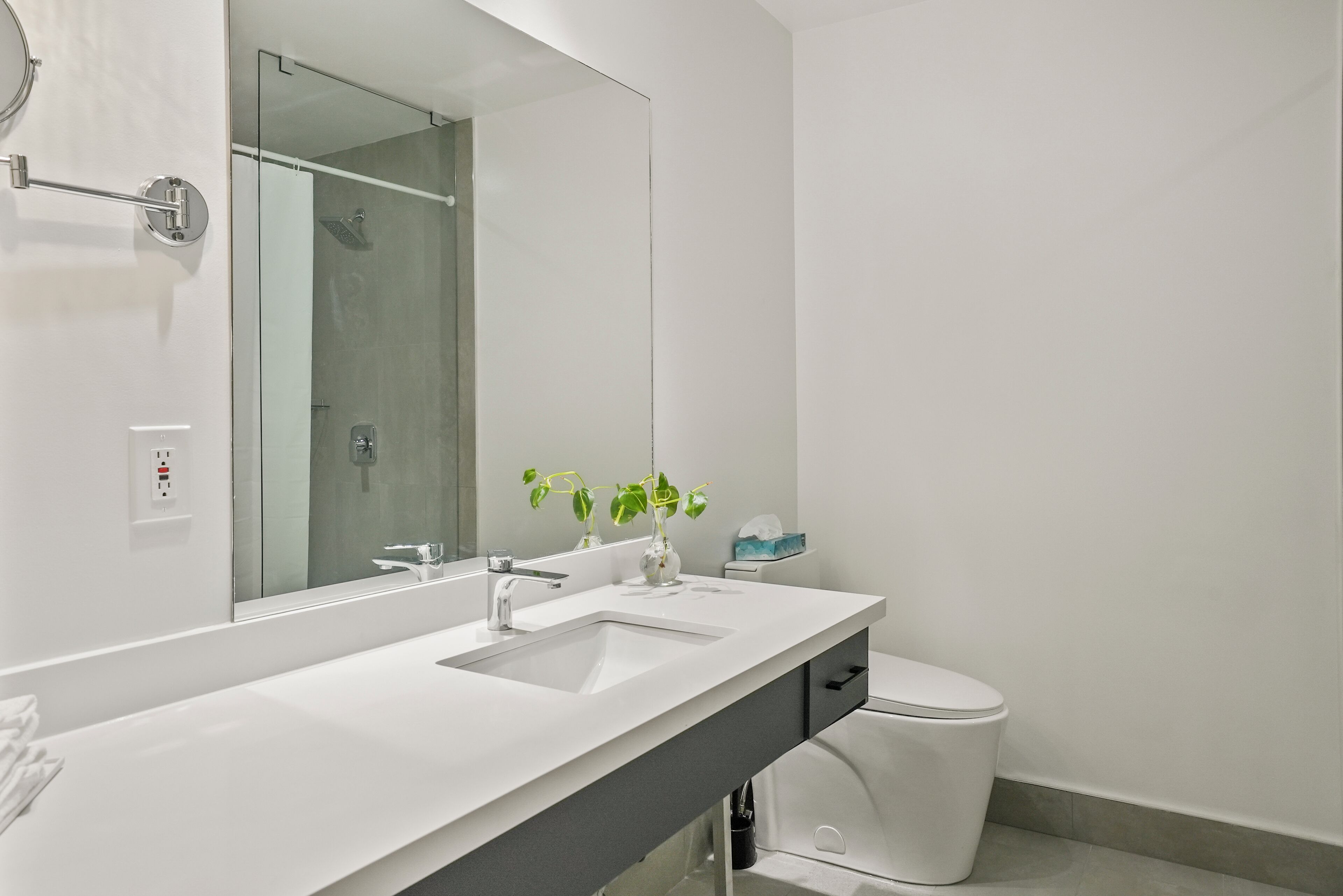 A modern bathroom with a white sink, a mirror, and a toilet.