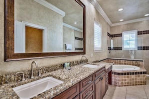 A bathroom with two sinks, a large mirror, and a bathtub.