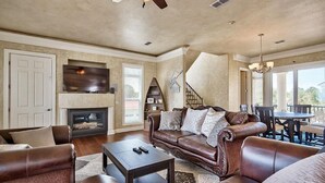 A spacious living room with a leather sofa, a fireplace, a television, and a dining area with a table and chairs. - Sea Span 6 Bedroom Holiday Home by Five Star Properties (Destin)