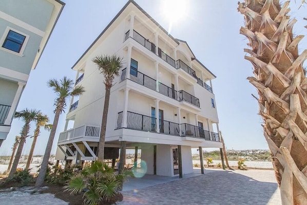 A multi-story hotel with balconies, palm trees, and a clear sky.