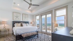 Un dormitorio con cama, una banca, un escritorio y un balcón con vistas.