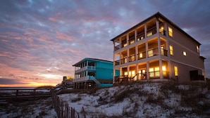 A two-story beachfront property with a balcony and a covered deck, surrounded by sand dunes. - Seaclusion 9 Bedroom Holiday Home by Five Star Properties (Miramar Beach)