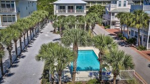 A resort with a central swimming pool surrounded by palm trees and multiple-story buildings with balconies. - SEAVIEW I UNIT 300 4 Bedroom Holiday Home by Five Star Properties (Santa Rosa Beach)