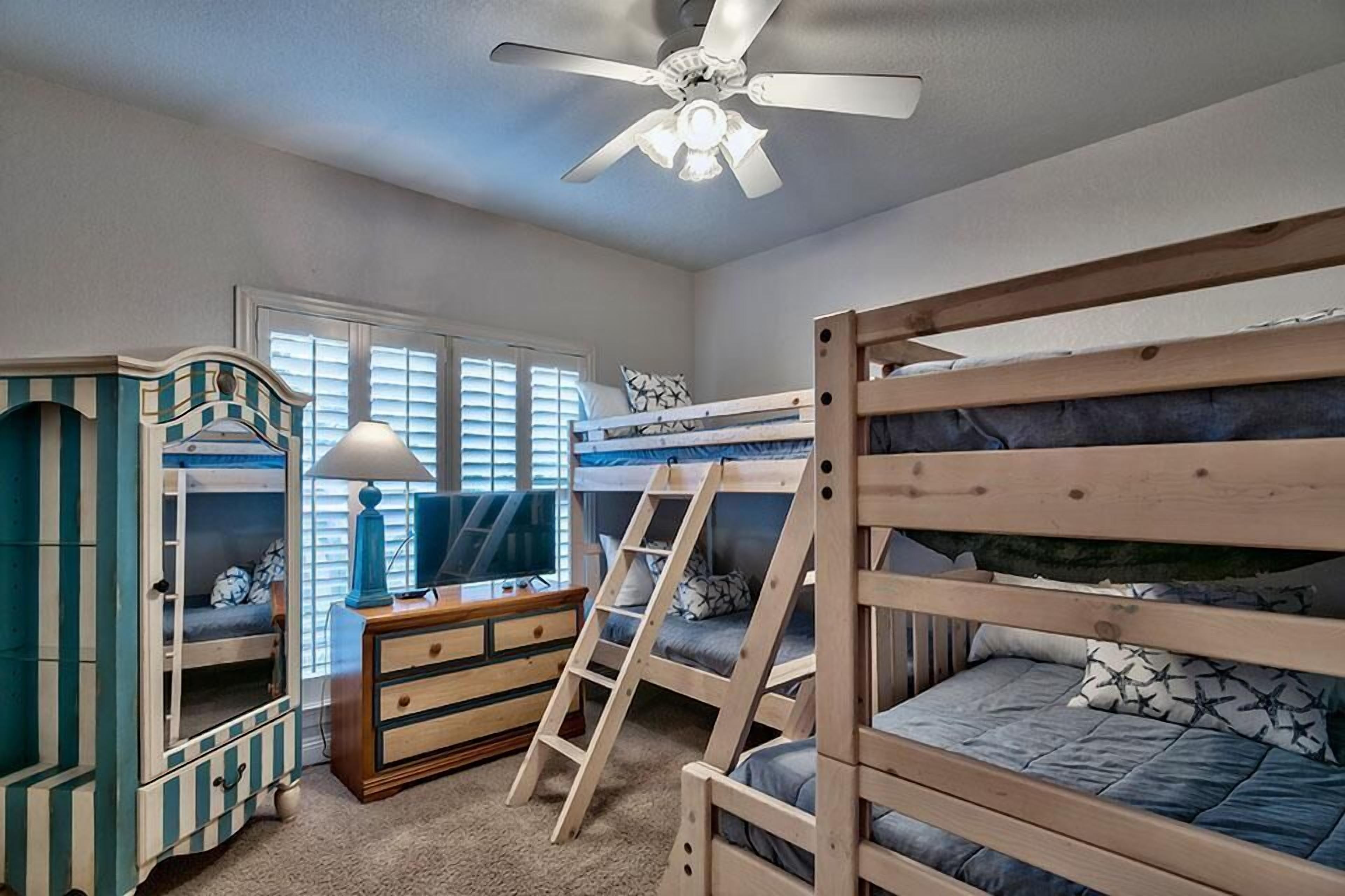 Habitación con literas, ventilador de techo, cómoda y televisor.