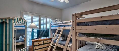 Habitación con literas, ventilador de techo, cómoda y televisor.