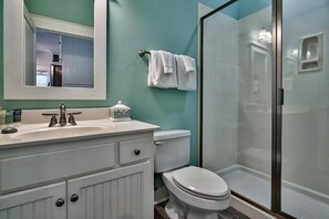 Een badkamer met een wit wastafel, toilet en een douche met glazen wanden.