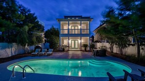 A two-story house with a swimming pool and outdoor seating.