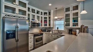A modern kitchen with white cabinetry, stainless steel appliances, and a large island.