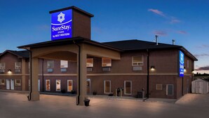 A SureStay hotel with a prominent blue sign, multiple entry points, and a covered parking area. - SureStay Studio by Best Western Hardisty (Hardisty)