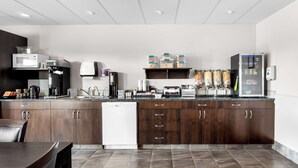 A modern kitchen with dark wood cabinets, a white dishwasher, a coffee machine, and a refrigerator. - SureStay Studio by Best Western Hardisty (Hardisty)