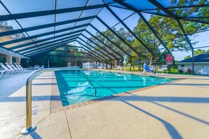 Une piscine dotée d’un espace couvert, de chaises longues et d’un panneau indiquant une réduction de 50 % sur l’utilisation de la piscine.