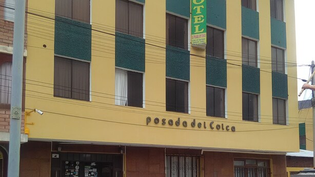Un hotel llamado 'Posada del Colco' con fachada amarilla, toldos verdes y un acceso empedrado de piedra.