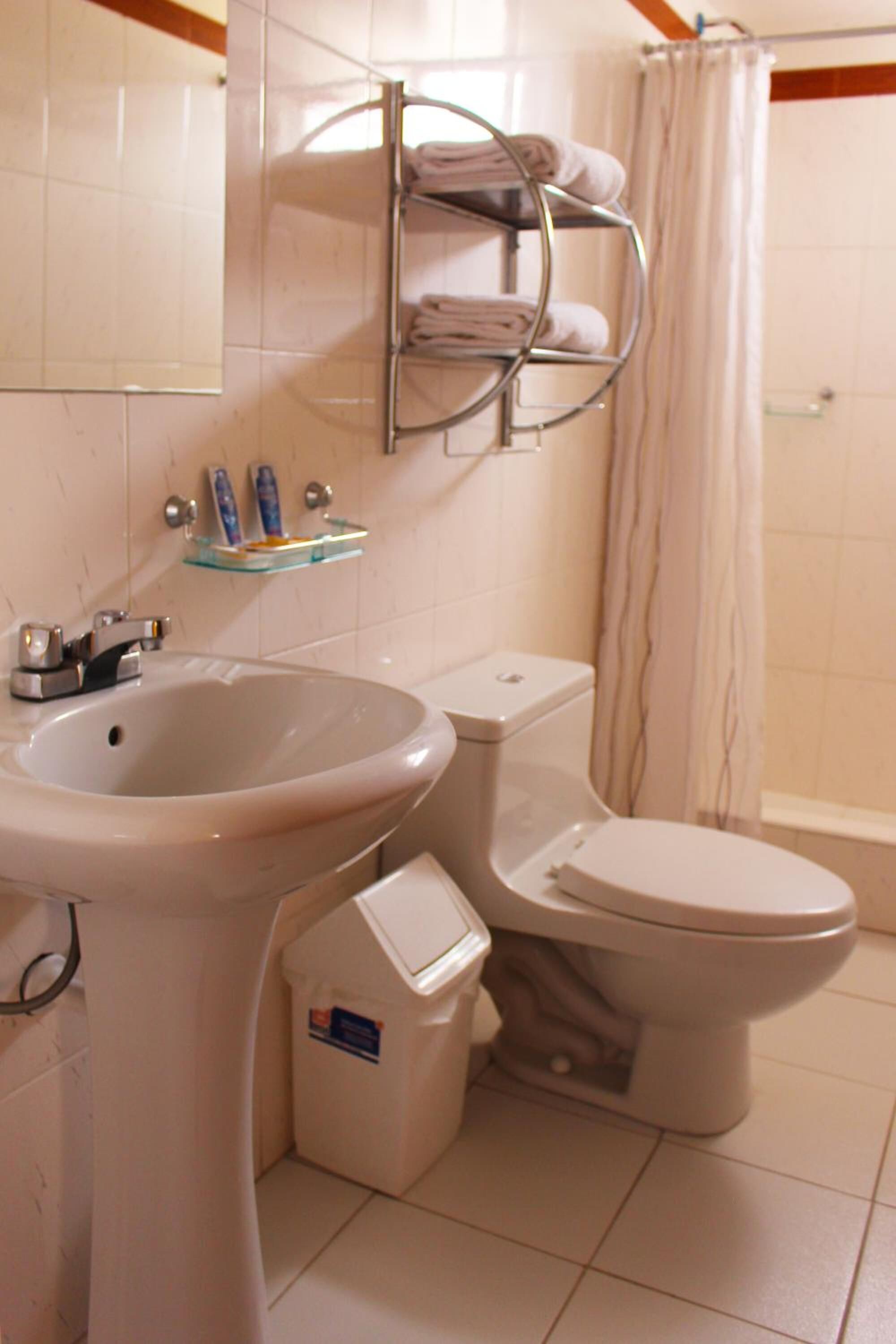 Un baño con lavamanos, inodoro y cortina de ducha.
