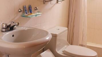 Un baño con lavamanos, inodoro y cortina de ducha.