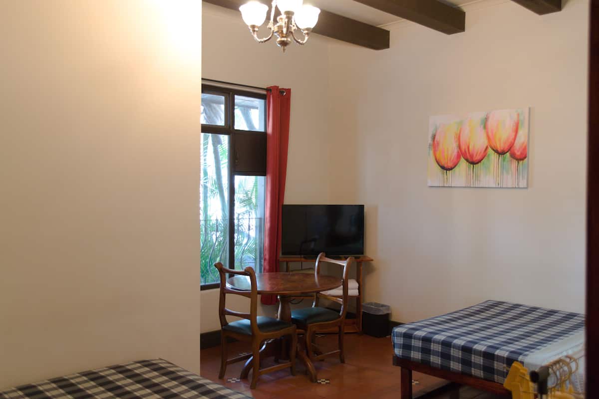 A dining area with a wooden table and chairs, a television, and a painting on the wall.