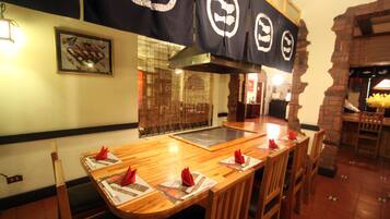 A restaurant with wooden tables and chairs, black banners with white logos, and a brick wall.