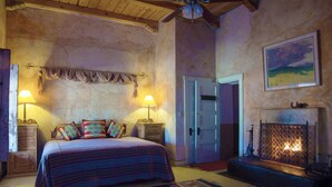 Une chambre à coucher avec un lit, deux tables de chevet, une cheminée et une porte.