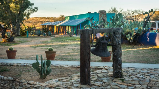 Un espace extérieur rustique agrémenté d’un clocheton en bois, de cactus en pot et d’un sentier en pierre.