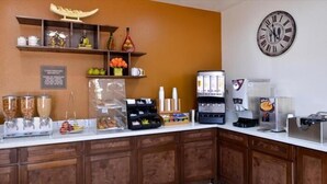 Una barra de desayuno con diferentes alimentos, una máquina de café y un reloj en la pared.